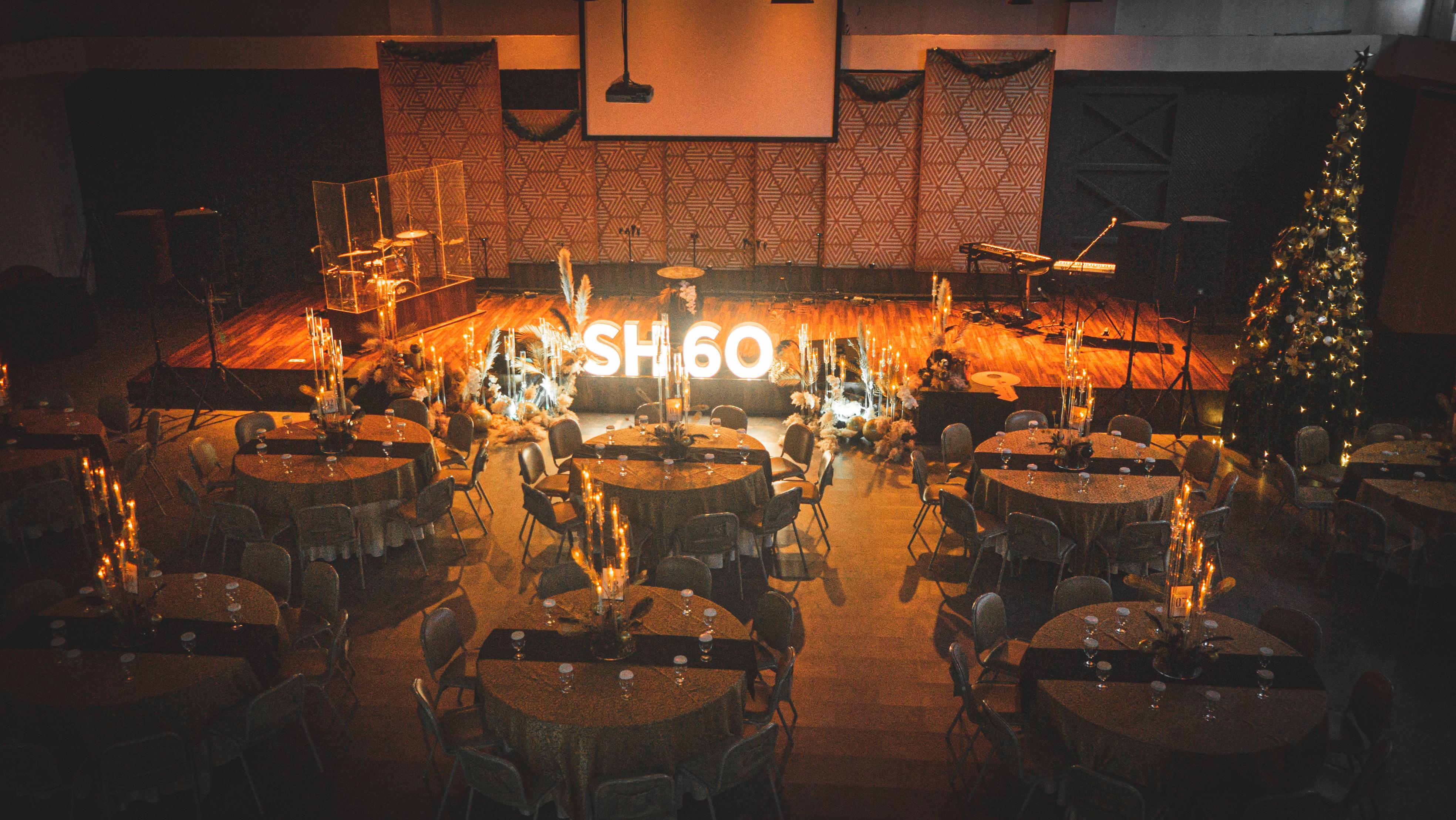 Sixtieth birthday celebration with banquet tables and stage at Heart Space 2.0